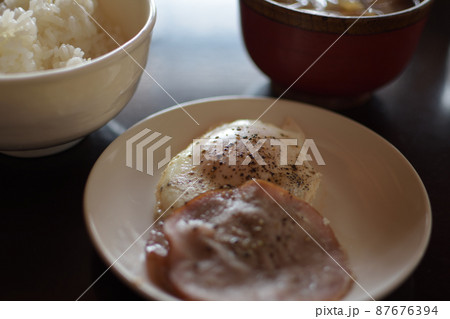大量の黒胡椒がかかっているハムエッグと、ご飯、味噌汁の食事 87676394
