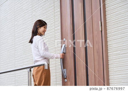 玄関ドアを開ける女性 87676997