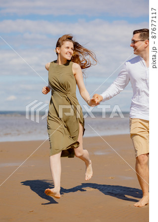 a couple of a man and a woman are walking on the beach or running along the sand along the seashore. beautiful and young  87677117