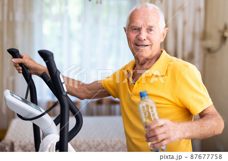 Man with bottle of water training with cross-trainer Man with bottle of water training with cross-trainer 87677758