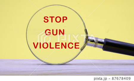 STOP GUN VIOLENCE inscription on a yellow background through a magnifying glass 87678409