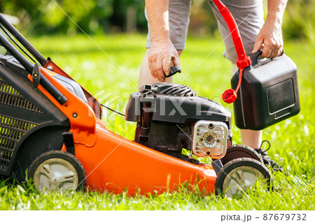 Man refueling the lawnmower on his huge garden, gardening concept 87679732