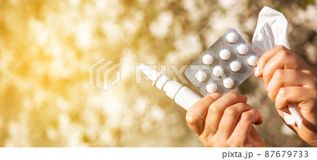 Woman holding allergy pills, drugs and nose spray against kind of an allergies during spring time, helathcare concept 87679733