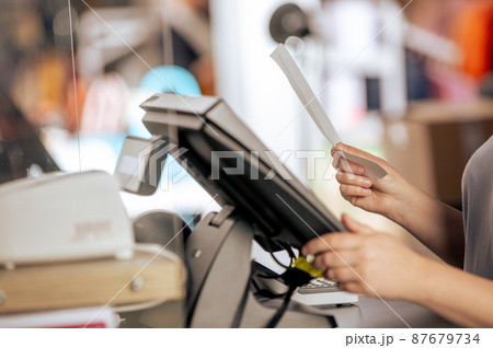Young woman doing process payment with the bill or invoice on the POS cash terminal in the shop, finance concept Young woman doing process payment with the bill or invoice on the POS cash terminal in the shop, finance concept 87679734