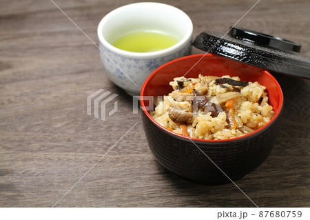 炊き込みご飯、蓋物の器に盛られた五目ご飯とお茶、木目バック 炊き込みご飯、蓋物の器に盛られた五目ご飯とお茶、木目バック 87680759