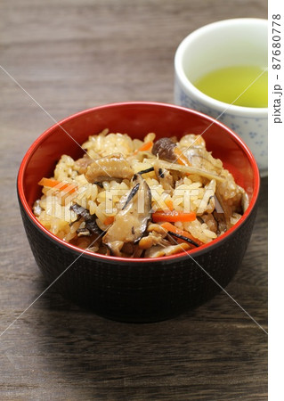 炊き込みご飯、蓋物の器に盛られた五目ご飯とお茶、木目バック 炊き込みご飯、蓋物の器に盛られた五目ご飯とお茶、木目バック 87680778