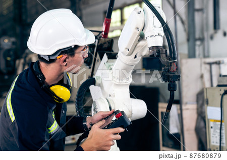 Young factory worker working with adept robotic arm 87680879