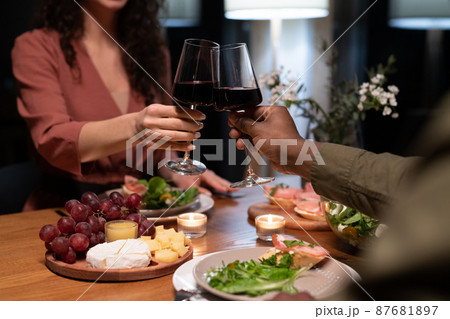 Hands of young interracial dates clinking with glasses of red wine Hands of young interracial dates clinking with glasses of red wine 87681897