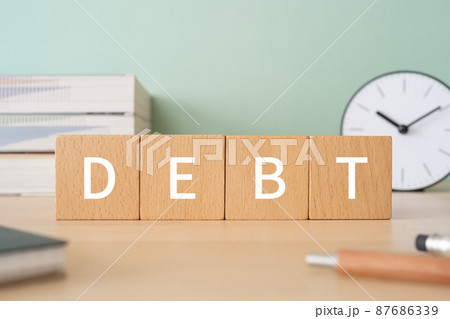 「DEBT」と書かれた積み木、参考書、時計、ノート、ペン 87686339