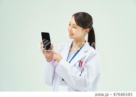 スマートフォンを持つ白衣の女性 87686385