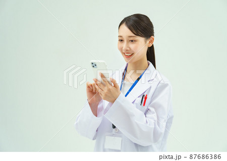 スマートフォンを持つ白衣の女性 87686386