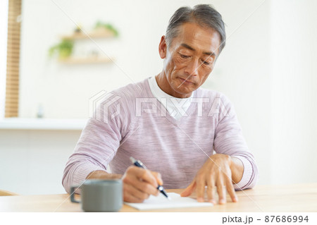 手紙を書くシニア男性 87686994