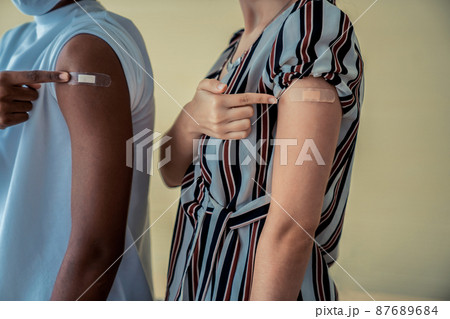 Diverse group of people showing COVID-19 vaccine bandage merrily Diverse group of people showing COVID-19 vaccine bandage merrily 87689684