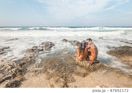 Couple of nudists kissing on beach near sea Couple of nudists kissing on beach near sea 87692172