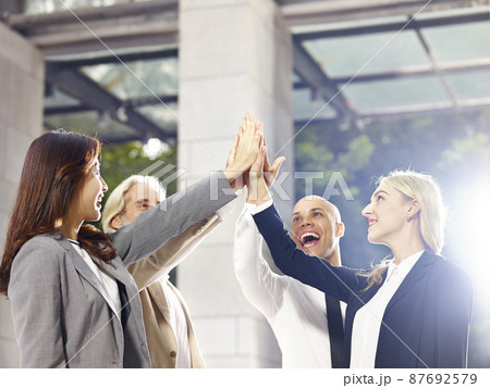 multi-ethnic corporate executives putting hands together celebrating achievement and success 87692579