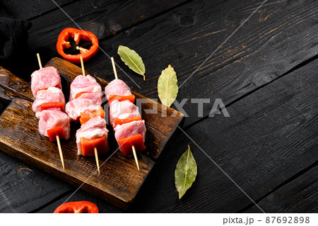 Uncooked Raw meat Chopsticks, with copy space for text, on black wooden table background 87692898