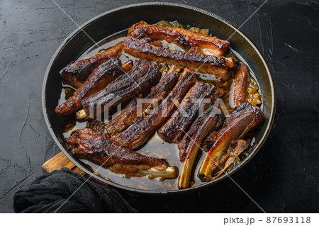 Grilled pork rib, in frying cast iron pan, on black stone background 87693118