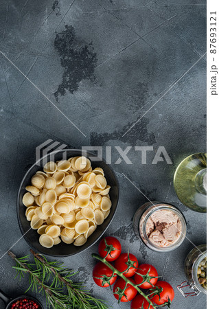 Whole wheat pasta with dried tomatoes and tuna ingredients, on gray background, flat lay with copy space for text Whole wheat pasta with dried tomatoes and tuna ingredients, on gray background, flat lay with copy space for text 87693121