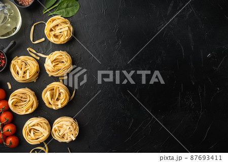 Fettuccine Tagliatelle pasta Italian food ingredients, on black stone background, top view flat lay, with copy space for text Fettuccine Tagliatelle pasta Italian food ingredients, on black stone background, top view flat lay, with copy space for text 87693411