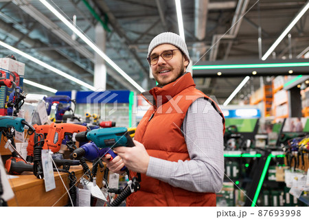 customer in a hardware store next to a showcase with power tools 87693998