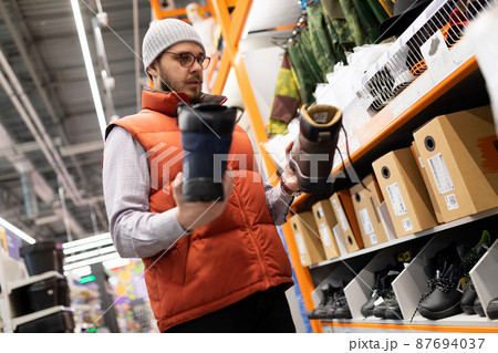 a customer in a hardware store chooses boots for work on a construction site, the concept of 87694037