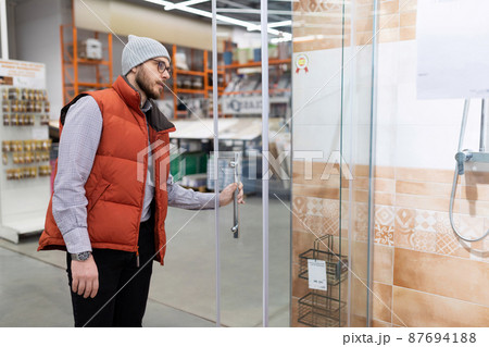 a man in a store examines a shower stall in the plumbing department a man in a store examines a shower stall in the plumbing department 87694188