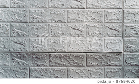 The wallpaper begins to peel off. Old white bricks wallpaper peeled off from the wall inside the room due to moisture or poor quality gluing. Repair and construction services concept. Selective Focus. The wallpaper begins to peel off. Old white bricks wallpaper peeled off from the wall inside the room due to moisture or poor quality gluing. Repair and construction services concept. Selective Focus. 87694620