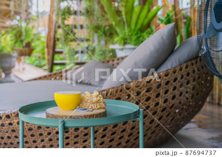 Hot coffee in a yellow cup and crispy lotus blossom cookie for relax time on wooden board at the balcony 87694737