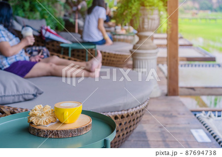 Hot coffee in a yellow cup and crispy lotus blossom cookie for relax time on wooden board at the balcony Hot coffee in a yellow cup and crispy lotus blossom cookie for relax time on wooden board at the balcony 87694738