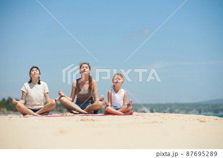 Women Meditating on Beach Women Meditating on Beach 87695289