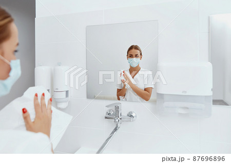 Hygiene, health care. Woman doctor or nurse drying hands with paper tissue at hospital after Washing Hands 87696896