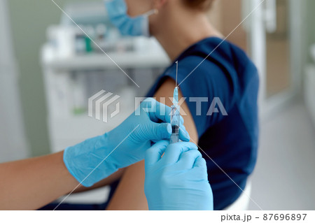 close up doctor holding syringe  make injection to patient in medical mask. Covid-19 or coronavirus vaccine 87696897
