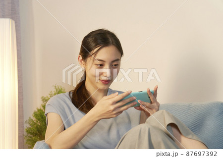 女性 スマホ 笑顔 リビング 夜 女性 スマホ 笑顔 リビング 夜 87697392