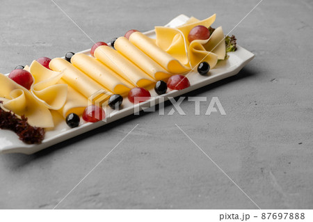 Cheese platter with grapes and black olives on gray background Cheese platter with grapes and black olives on gray background 87697888