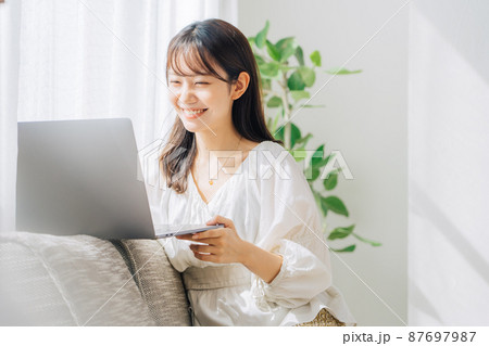 ソファでパソコンを使う女性 87697987