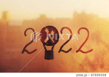 numbers 2022 of new year with balloon shape paint with finger on splashed by rain foggy glass on sunset orange window 87699308