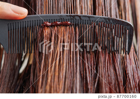 Young female hairdressed hands dyeing long hair to beautiful girl. Barber hair dye is applied with a brush 87700160
