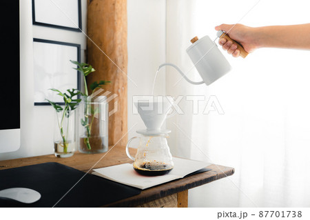 Drip coffee,Pouring a hot water over a drip coffee on the table Drip coffee,Pouring a hot water over a drip coffee on the table 87701738