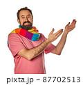 excited bearded man in the 40s, pointing to copy space with two hands outstretched on white background. casual wear and scarf lgtbq concept 87702513