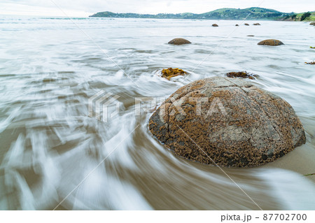 ニュージーランド　モエラキの海岸にある丸い奇石、モエラキ・ボルダーズと打ち寄せる波 87702700