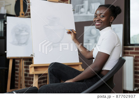 Portrait of student smiling and drawing sketch on canvas during creative art class 87702937