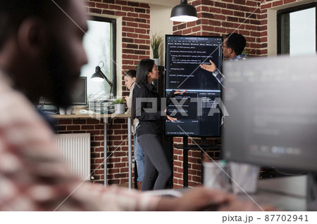 Software developers standing near vertical screen talking about interface bug 87702941