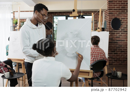 Painter teacher explaining illustration technique to student 87702942