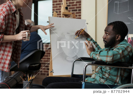 Painter teacher showing drawing technique to impaired student 87702944