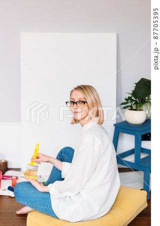 Young woman artist is painting at home in a creative studio setting. Young woman artist is painting at home in a creative studio setting. 87705395