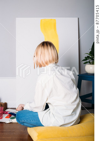 Young woman artist is painting at home in a creative studio setting.  87705415