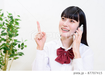 スマートフォンを持ってアイデアを提案して笑顔で通話する女子高校生　電話をかける　話を聞く　相談 87707415