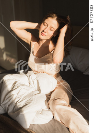 Girl is waking up in morning stretches in bed and sun shines from the window. Happy young woman greets new sunny day Girl is waking up in morning stretches in bed and sun shines from the window. Happy young woman greets new sunny day 87707888