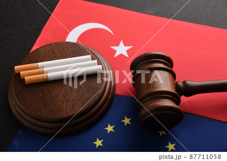 Illegal import of tobacco products. Cigarettes, Judge gavel on the flag of Turkey and the European Union. Illegal import of tobacco products. Cigarettes, Judge gavel on the flag of Turkey and the European Union. 87711058