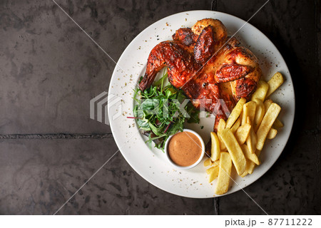 fried chicken tobacco with french fries and tomato sauce on a dark background. top view fried chicken tobacco with french fries and tomato sauce on a dark background. top view 87711222